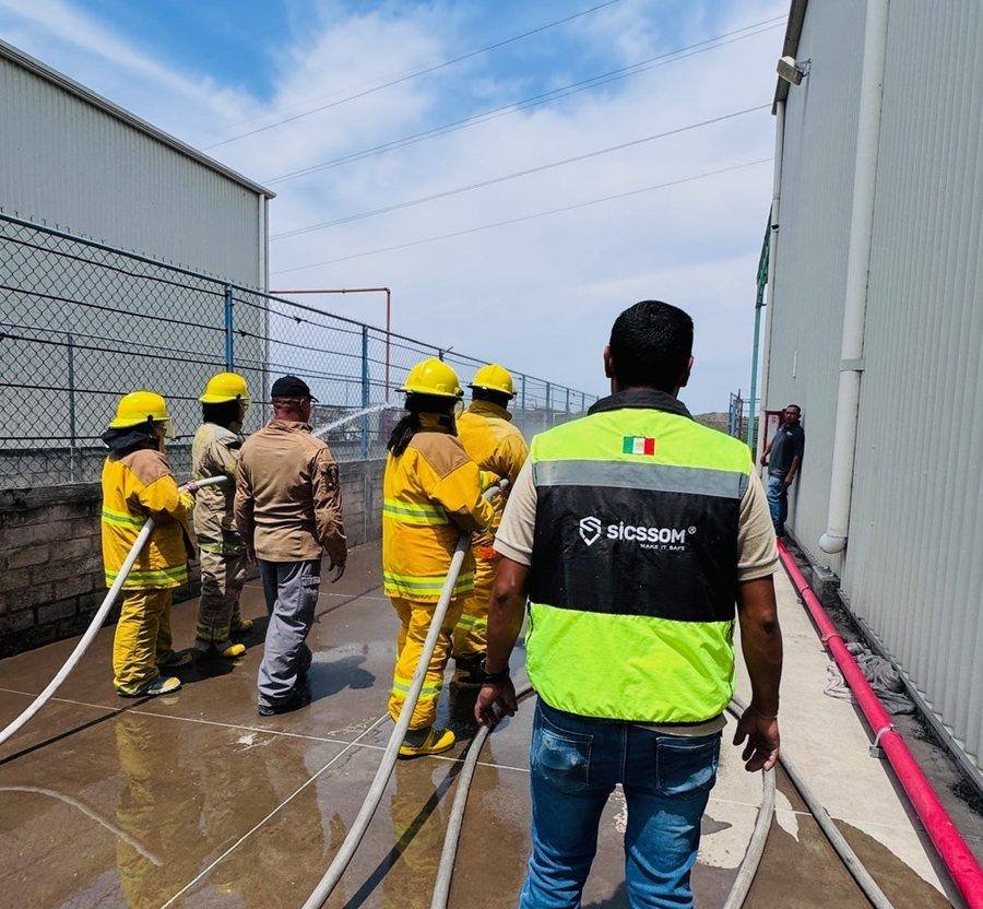Instructor de SICSSOM dirigiendo la práctica de brigada con manguera